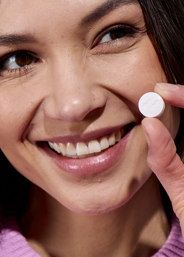 Smiling woman holding a Neuro Energy and Focus mint between her fingers